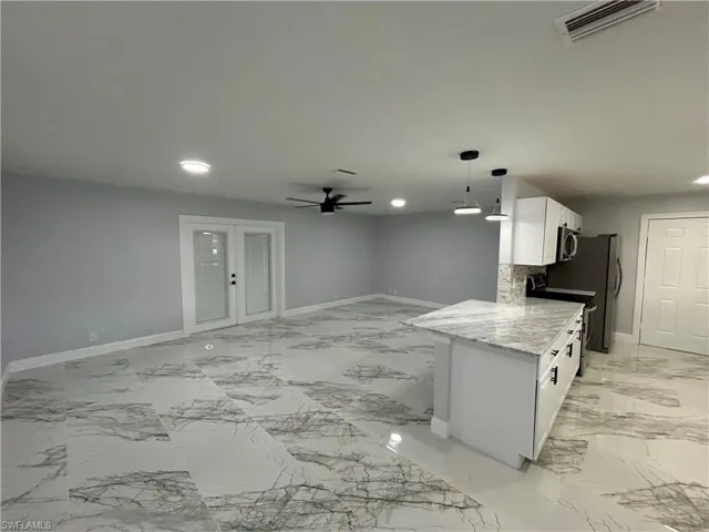 Kitchen with stainless steel appliances, ceiling fan, white cabinets, and light tile floors