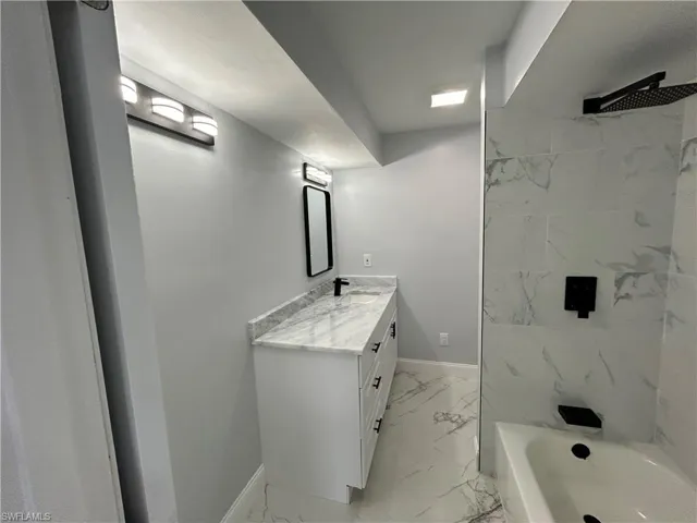 Bathroom with tile flooring, tiled shower / bath combo, and vanity