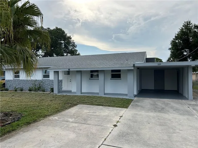Ranch-style house featuring a carport and a front lawn