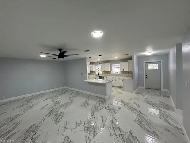 Unfurnished living room with ceiling fan and light tile floors