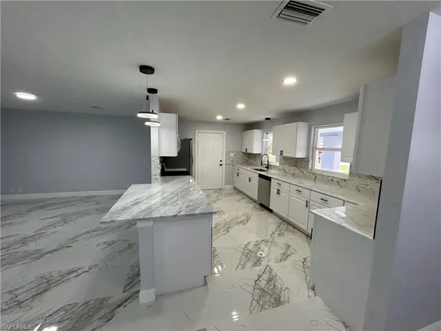 Kitchen featuring white cabinets, backsplash, fridge, sink, and light tile floors