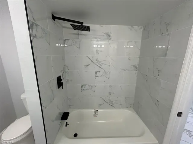 Bathroom with tiled shower / bath and toilet