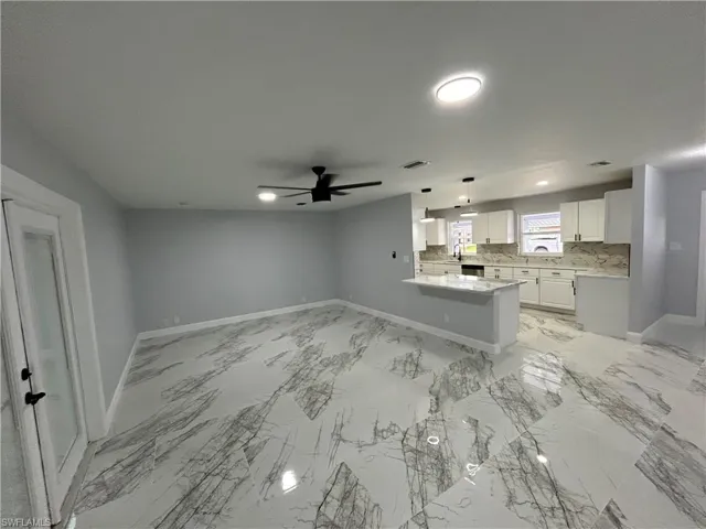 Unfurnished living room with ceiling fan and light tile floors
