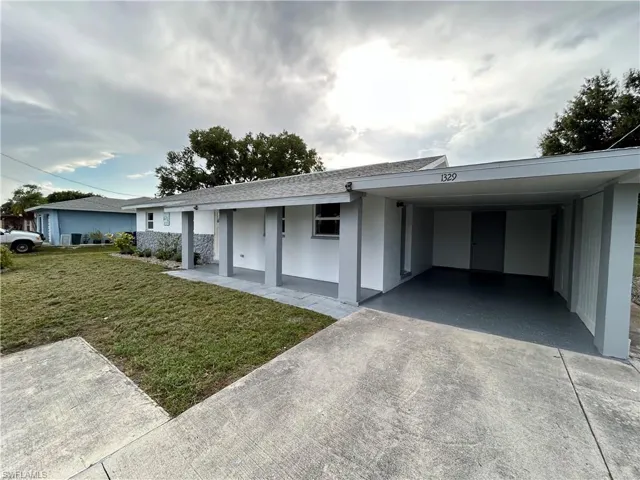 Single story home featuring a carport and a front lawn