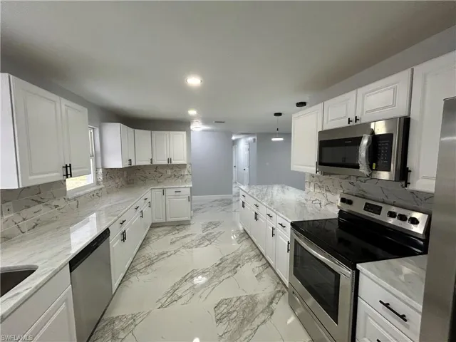 Kitchen featuring white cabinetry, backsplash, light tile flooring, and stainless steel appliances