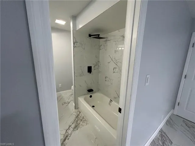 Bathroom featuring tile flooring, toilet, and tiled shower / bath