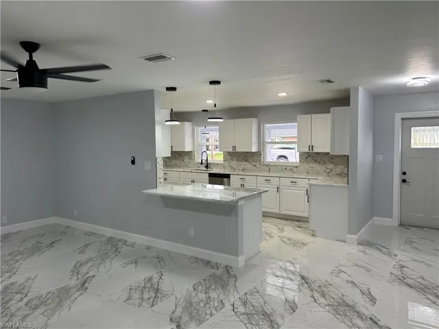 Kitchen with white cabinetry, backsplash, pendant lighting, sink, and ceiling fan