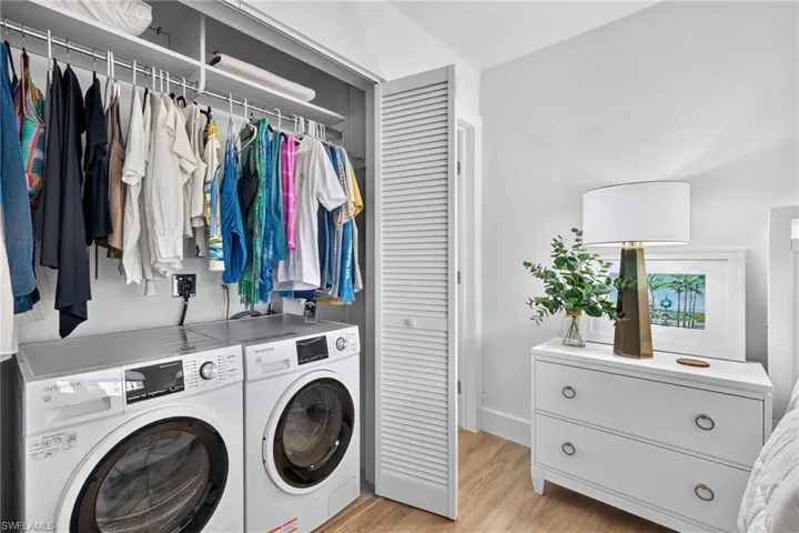 Integrated laundry closet featuring a stacked washer and dryer, upper shelving, and a hanging clothes rod