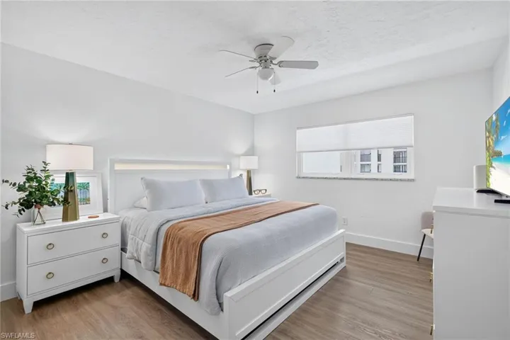 Bright room featuring wood-finish flooring, a white ceiling fan, and a window with blinds