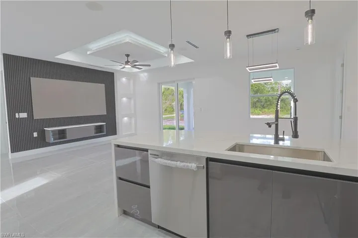 Kitchen featuring light stone countertops, decorative light fixtures, stainless steel dishwasher, modern cabinets, and light tile patterned floors