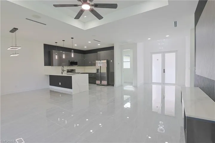 Kitchen featuring modern cabinets, stainless steel appliances, a peninsula, open floor plan, and a raised ceiling