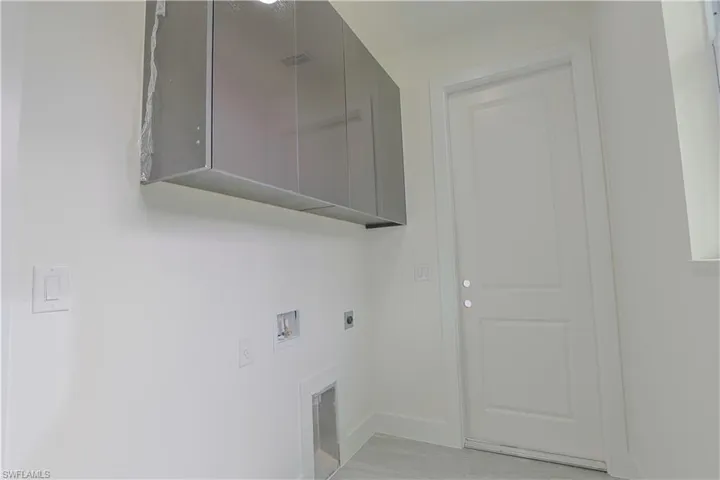 Laundry room with hookup for a washing machine, cabinet space, electric dryer hookup, and light tile patterned floors