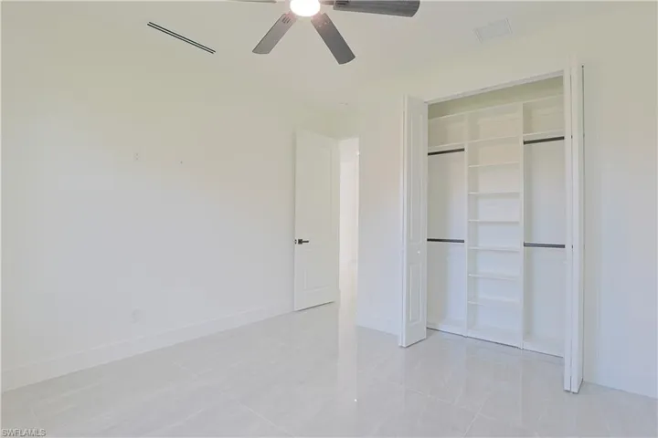 Unfurnished bedroom featuring a ceiling fan, light tile patterned flooring, and a closet