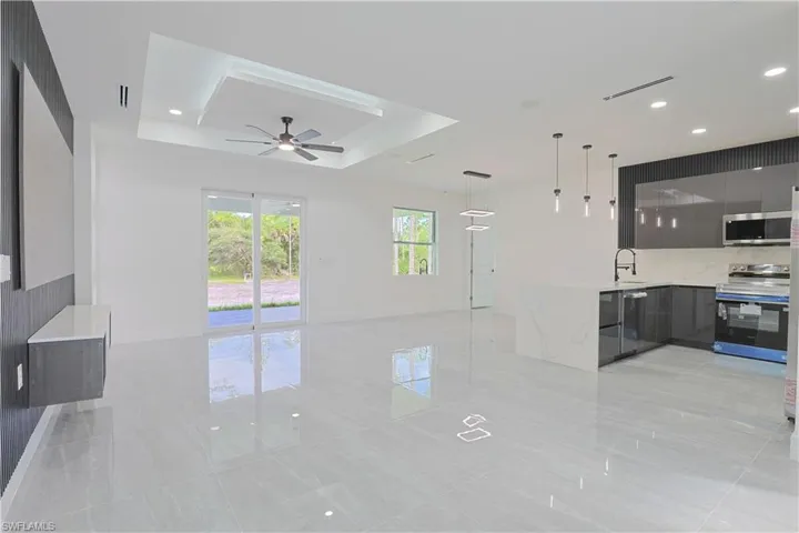 Unfurnished living room featuring recessed lighting, a tray ceiling, ceiling fan, and light tile patterned floors