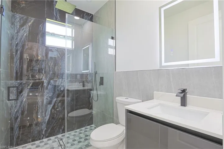 Bathroom featuring a marble finish shower, vanity, and tile walls