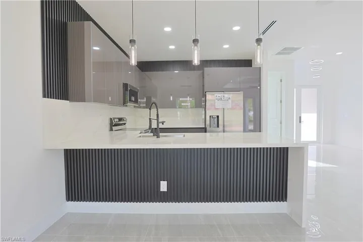 Kitchen featuring a peninsula, modern cabinets, light stone counters, stainless steel appliances, and recessed lighting