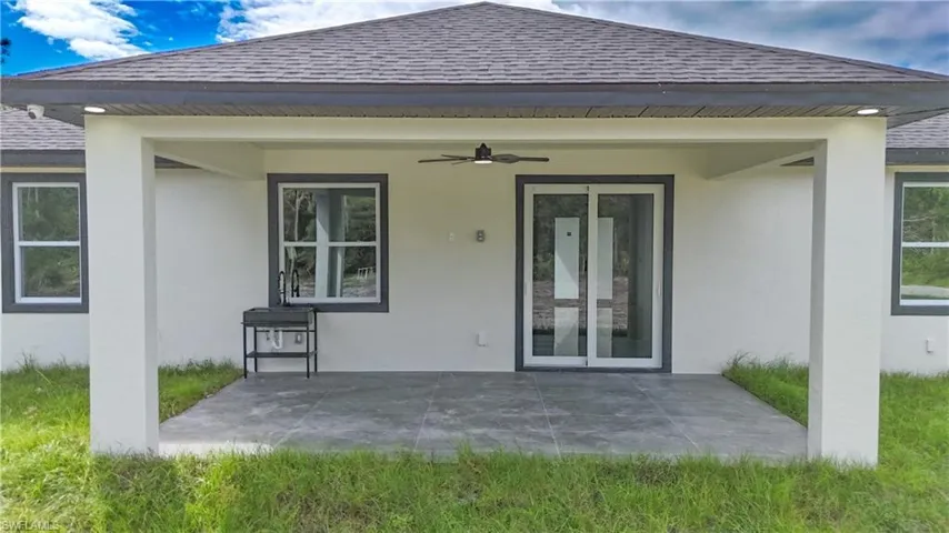 Rear view of house with a ceiling fan, a shingled roof, a patio area, and stucco siding