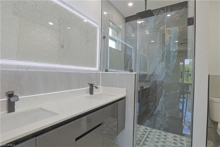 Full bathroom featuring a marble finish shower and double vanity