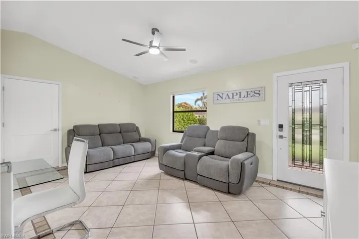 Tiled living room with ceiling fan and lofted ceiling