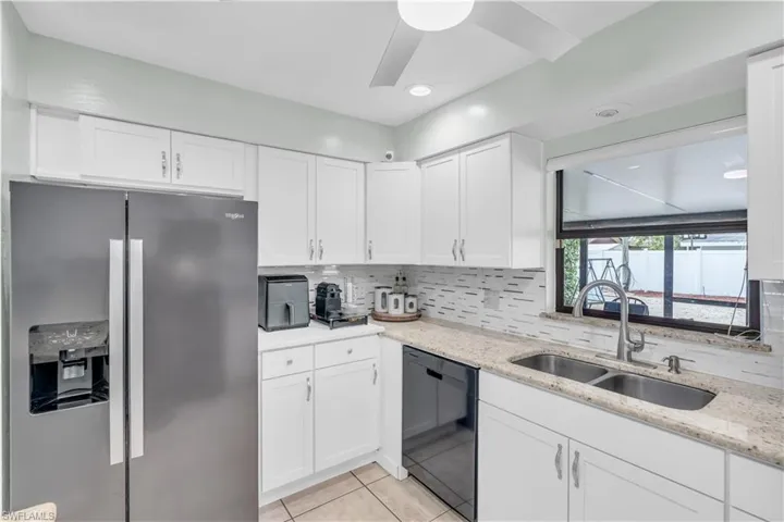Kitchen with white cabinetry, dishwasher, sink, and stainless steel fridge with ice dispenser