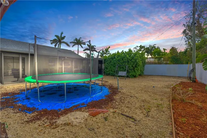 Yard at dusk featuring a trampoline