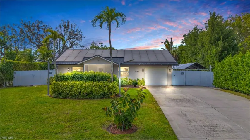 View of front of home with a garage, a yard, and solar panels