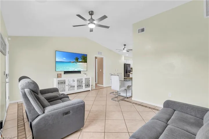 Tiled living room featuring lofted ceiling and ceiling fan
