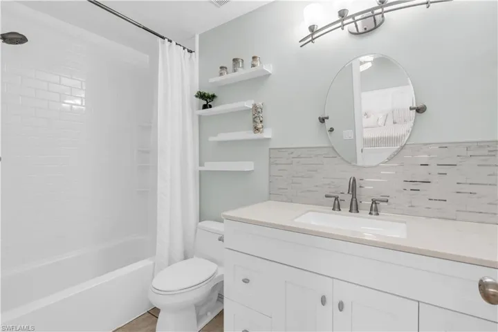 Full bathroom featuring backsplash, vanity, toilet, and shower / bath combo