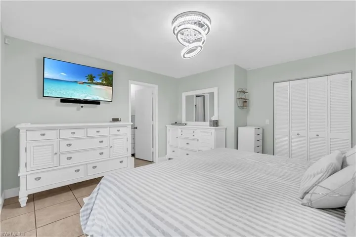 Bedroom with light tile patterned floors, a notable chandelier, and a closet
