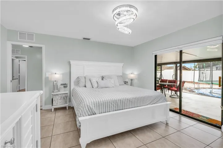 Bedroom featuring access to exterior, a chandelier, and light tile patterned floors