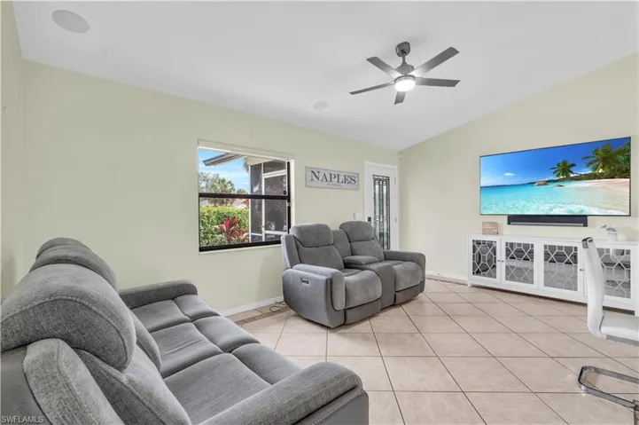 Living room featuring lofted ceiling, light tile patterned floors, and ceiling fan
