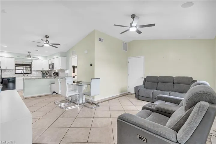 Living room with light tile patterned flooring, ceiling fan, and lofted ceiling