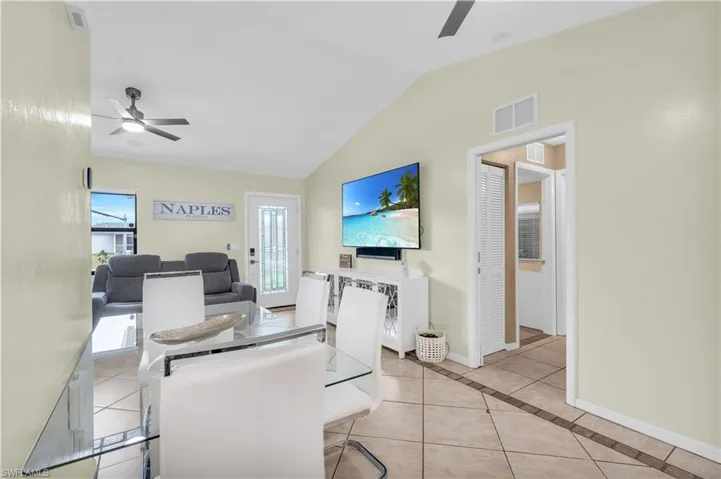 Living room featuring lofted ceiling, ceiling fan, and light tile patterned flooring