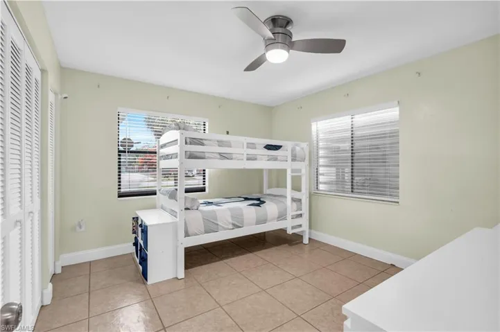 Bedroom with light tile patterned flooring, ceiling fan, and a closet