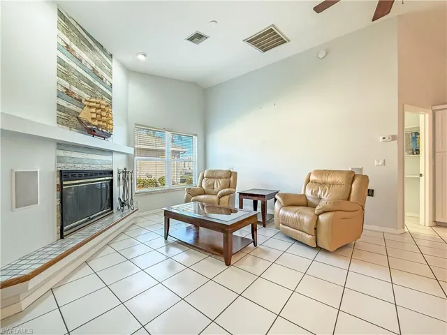 Living area featuring built in fire place, shelves, tile flooring, high vaulted ceiling, and ceiling fan