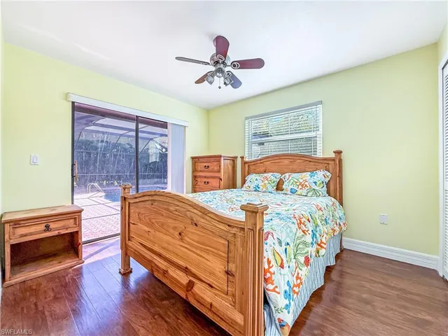 Bedroom with dark wood-type flooring, access to outside, and multiple windows