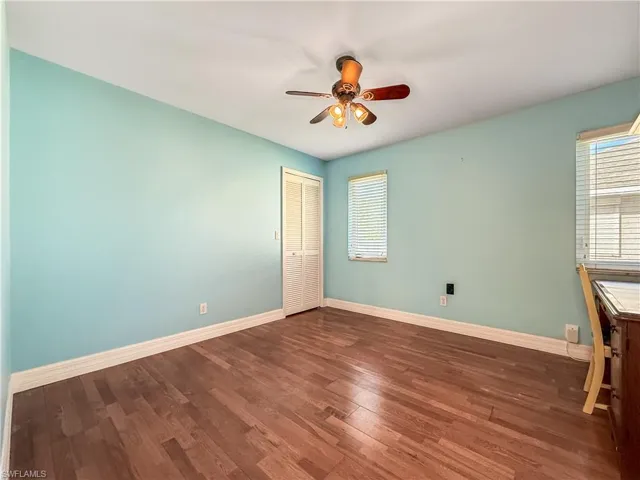 Unfurnished room featuring dark wood-style floors, ceiling fan, and healthy amount of natural light