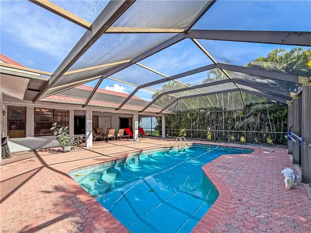Outdoor pool featuring a patio area, glass enclosure, and a sunroom