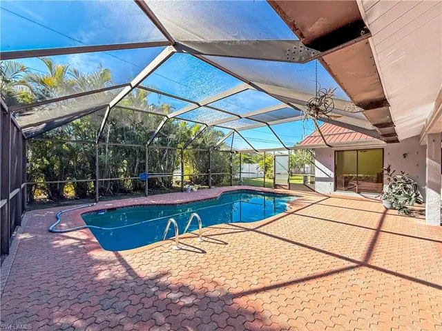 Outdoor pool with a patio, a sunroom, and a lanai