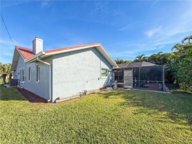 View of home's exterior featuring a lanai, stucco siding, a yard, and a chimney