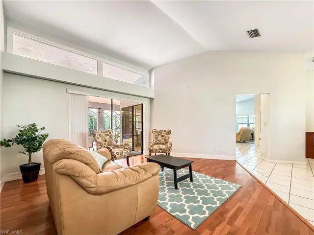 Living area with plenty of natural light, wood finished floors, and vaulted ceiling