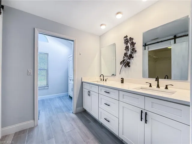 Bathroom with double vanity, a spacious closet, and wood tiled floors
