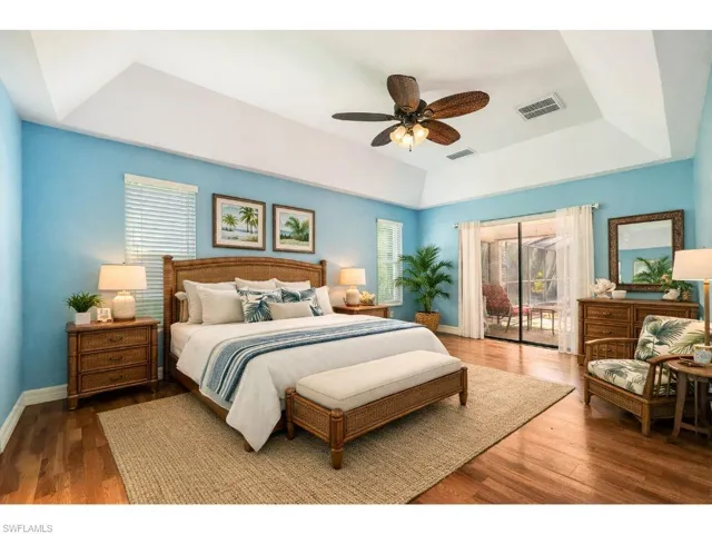 Staged Bedroom featuring a tray ceiling, access to exterior, wood finished floors, and a ceiling fan