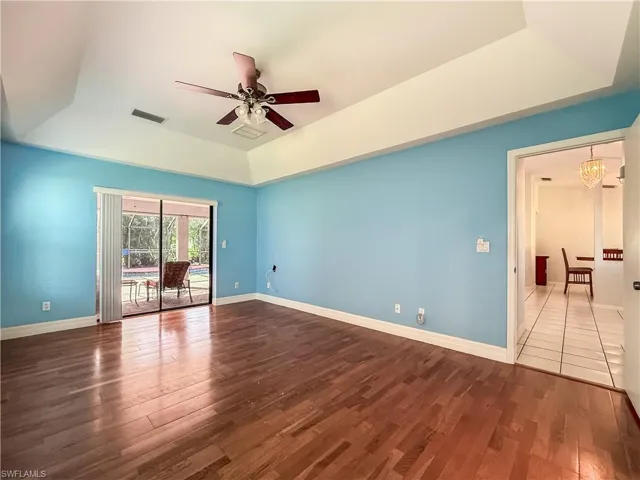 Unfurnished room with a tray ceiling, hardwood / wood-style floors, and a ceiling fan