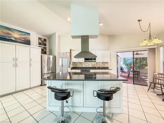 Kitchen featuring a kitchen breakfast bar, high end refrigerator, island exhaust hood, pantry and hanging light fixtures