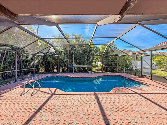 Outdoor pool with glass enclosure, a sunroom, and a patio area