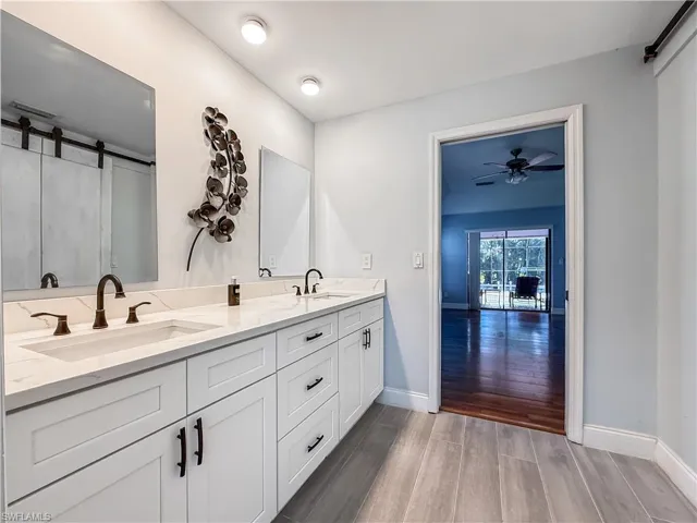 Full bath with dark wood finished floors, double vanity, a shower with curtain, and ceiling fan