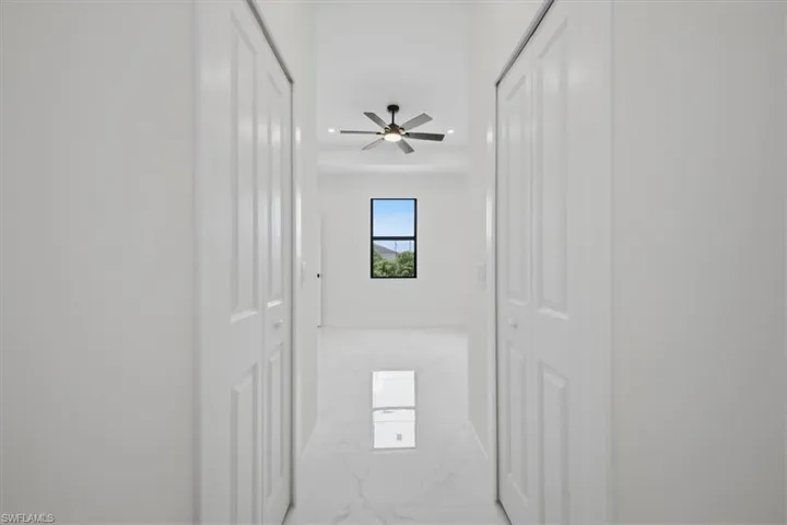 Hallway featuring white bi-fold doors, recessed lighting, and large format tile flooring