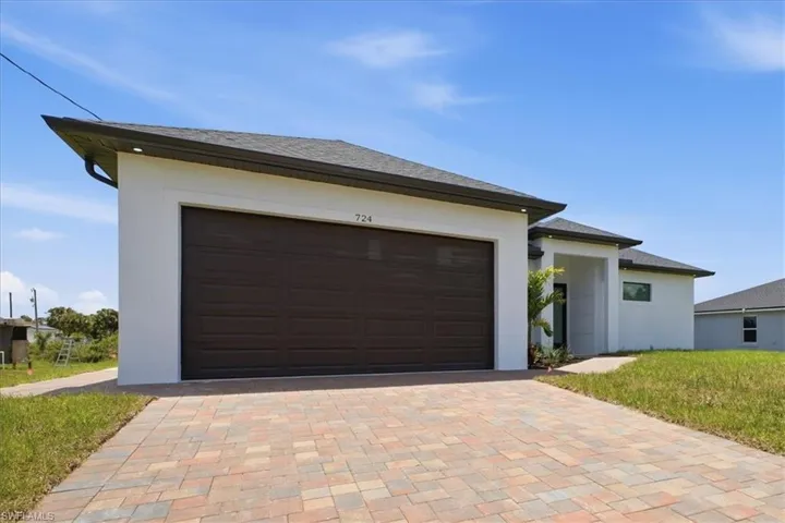 Contemporary-style residence with a dark brown garage door, white stucco exterior, and a multi-toned paver driveway