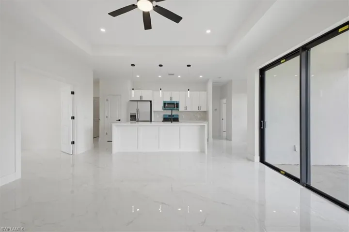 Open-concept living space featuring a contemporary kitchen, wood-finish flooring, and a large sliding glass door